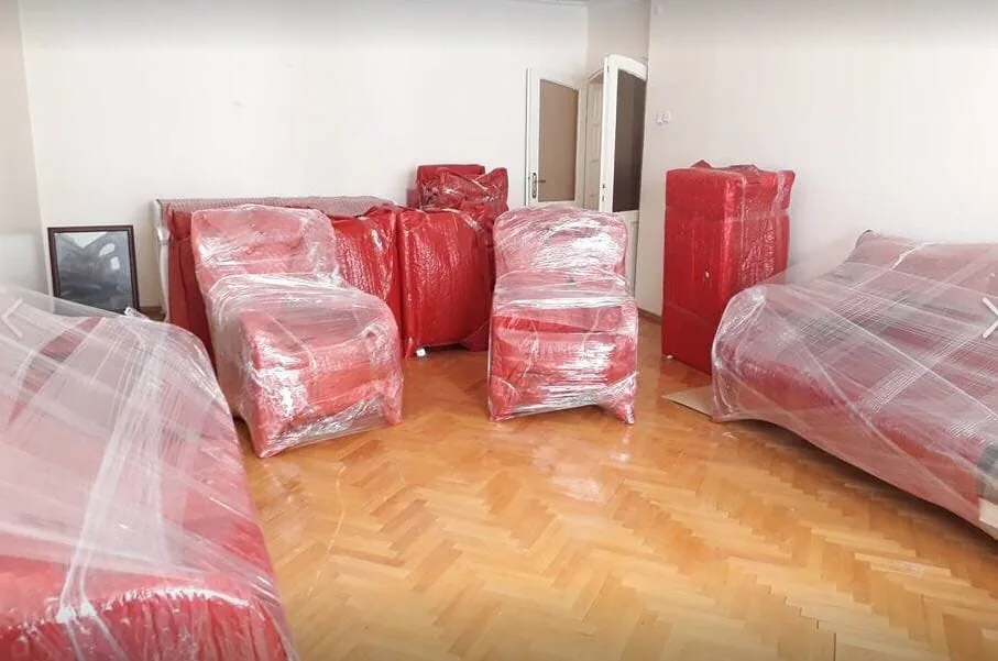 Taşıma öncesinde kırmızı koruyucu malzeme ile paketlenmiş ev eşyaları